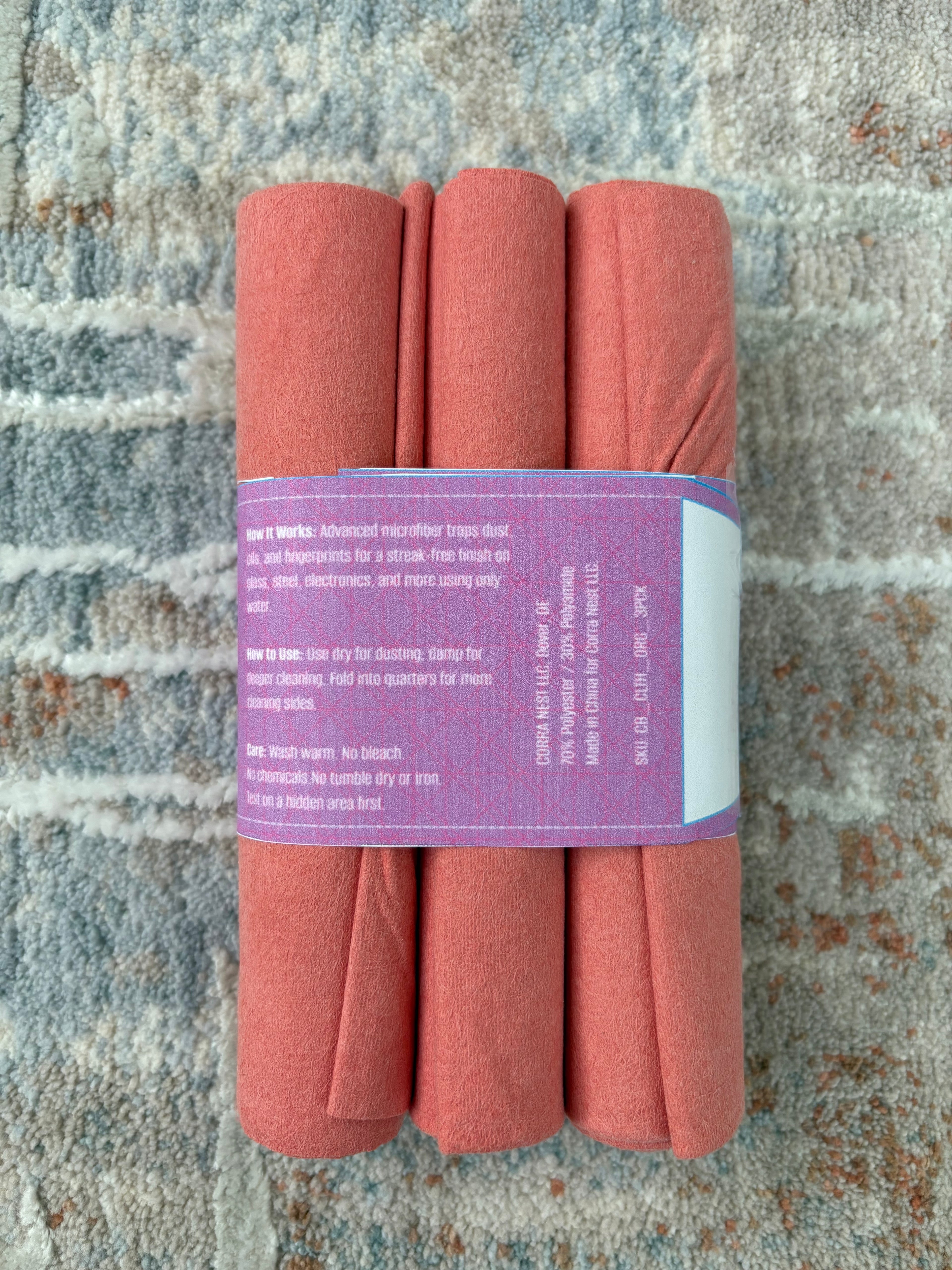 Three folded pink towels with a purple label on a textured stone surface